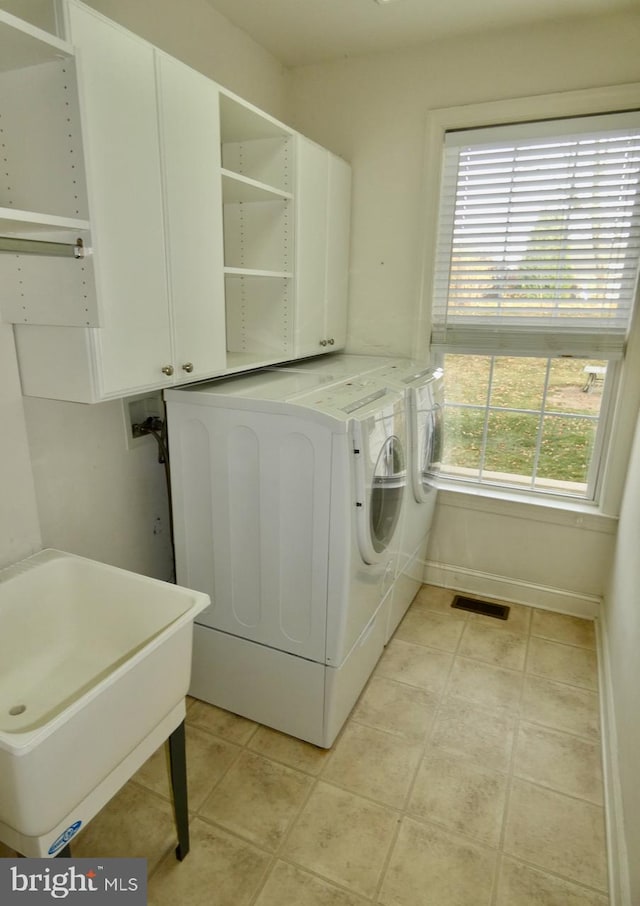 laundry area featuring cabinets, separate washer and dryer, light tile patterned floors, and sink