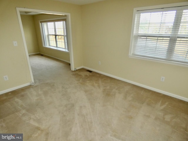 carpeted spare room featuring plenty of natural light