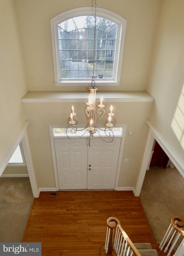 foyer entrance featuring hardwood / wood-style floors, a healthy amount of sunlight, and a chandelier