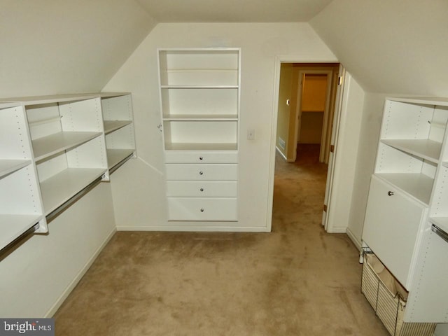 spacious closet with light colored carpet and lofted ceiling