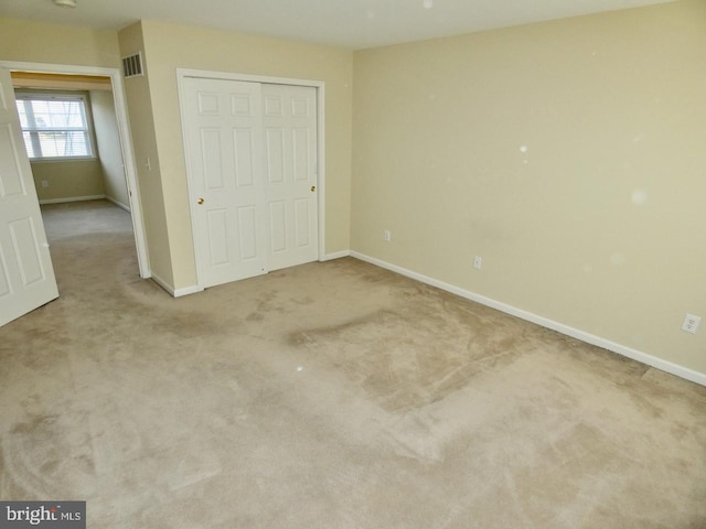 unfurnished bedroom with a closet and light carpet