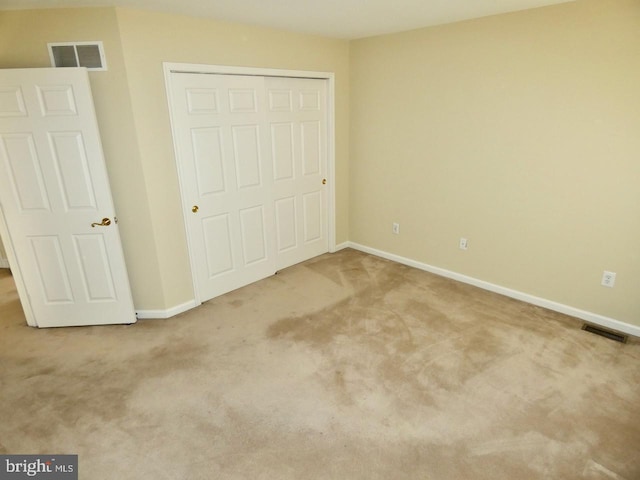 unfurnished bedroom featuring a closet and light colored carpet