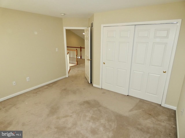 unfurnished bedroom with light colored carpet and a closet