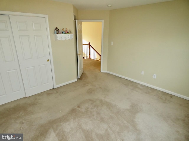 unfurnished bedroom featuring light carpet and a closet