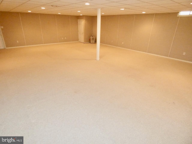 basement featuring a paneled ceiling and carpet floors