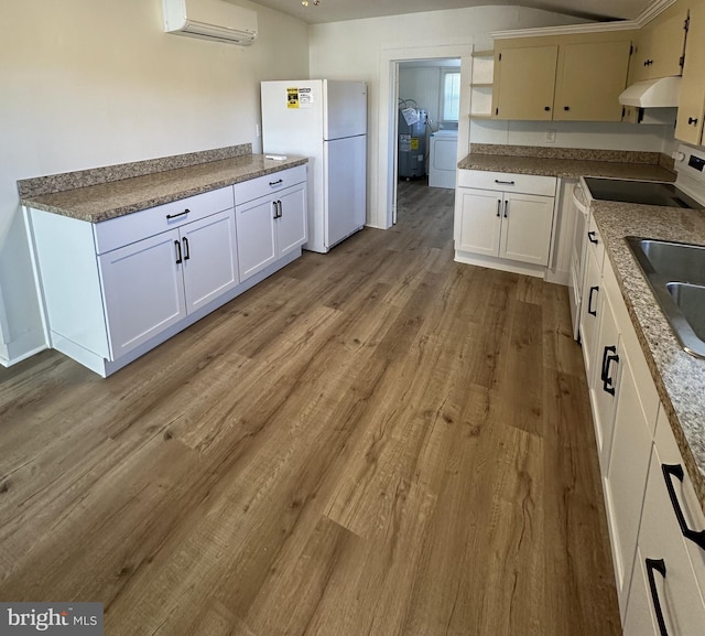 kitchen featuring a wall mounted air conditioner, white cabinets, white fridge, and light wood-type flooring