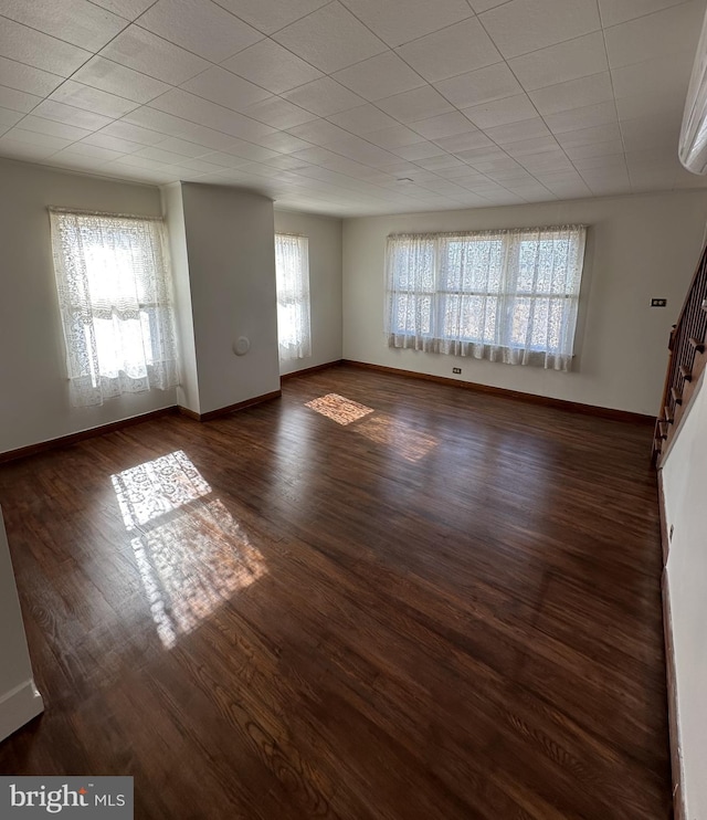 unfurnished living room featuring plenty of natural light and dark hardwood / wood-style floors