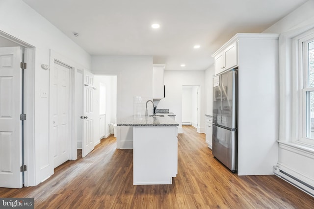 kitchen with white cabinetry, a baseboard heating unit, hardwood / wood-style floors, and stainless steel fridge