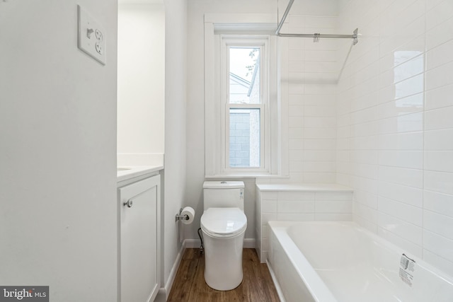 full bathroom featuring vanity, hardwood / wood-style floors, tiled shower / bath combo, and toilet