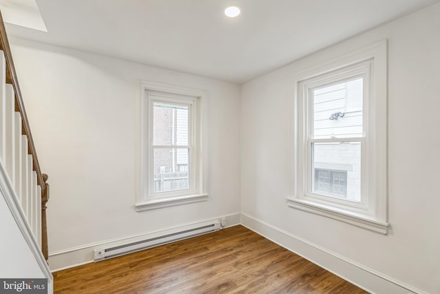 unfurnished room featuring a baseboard heating unit and hardwood / wood-style floors