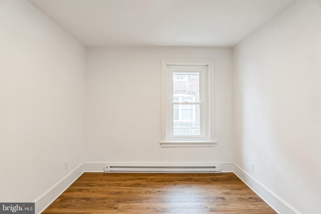 spare room with baseboard heating and wood-type flooring