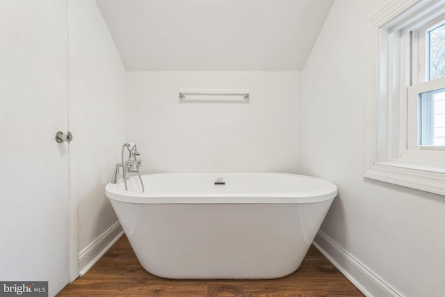 bathroom featuring lofted ceiling, hardwood / wood-style flooring, and a washtub