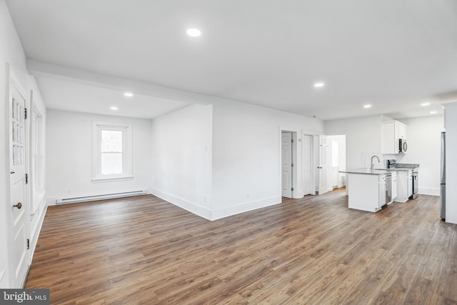 unfurnished living room with sink, light hardwood / wood-style flooring, and baseboard heating