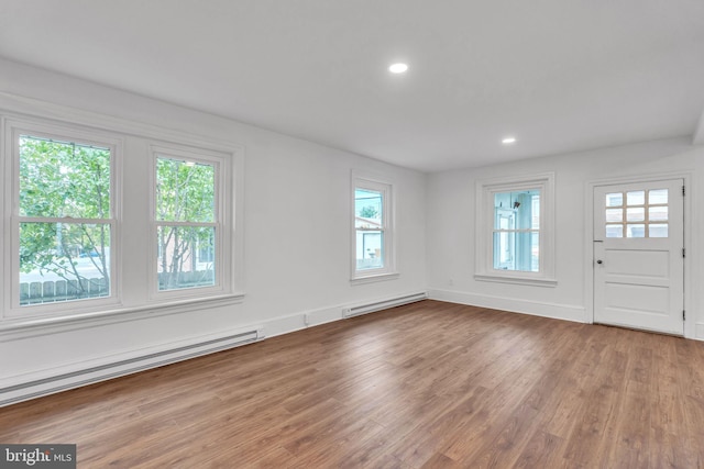 foyer entrance featuring baseboard heating, wood-type flooring, and plenty of natural light