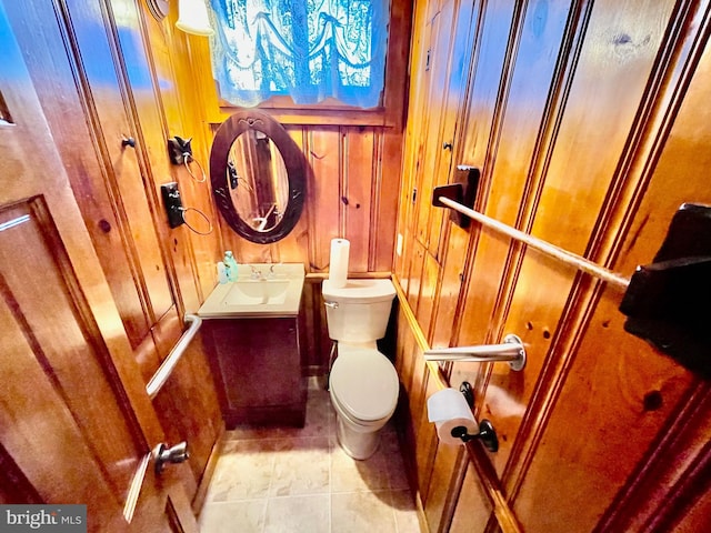 bathroom featuring vanity, toilet, wood walls, and tile patterned flooring