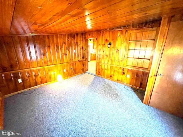 carpeted empty room featuring wooden ceiling and wooden walls