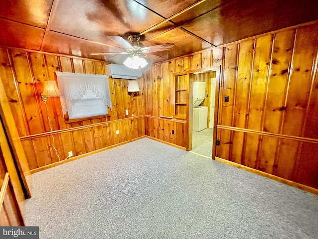 interior space with a wall mounted AC, washer / dryer, wooden walls, carpet flooring, and ceiling fan