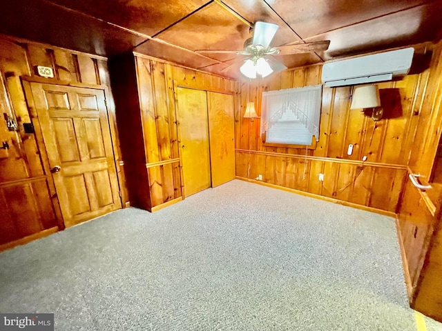 basement featuring ceiling fan, an AC wall unit, carpet flooring, and wooden walls