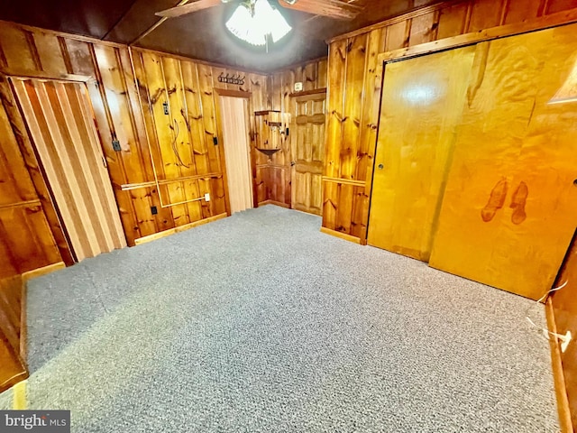 basement with ceiling fan and wood walls