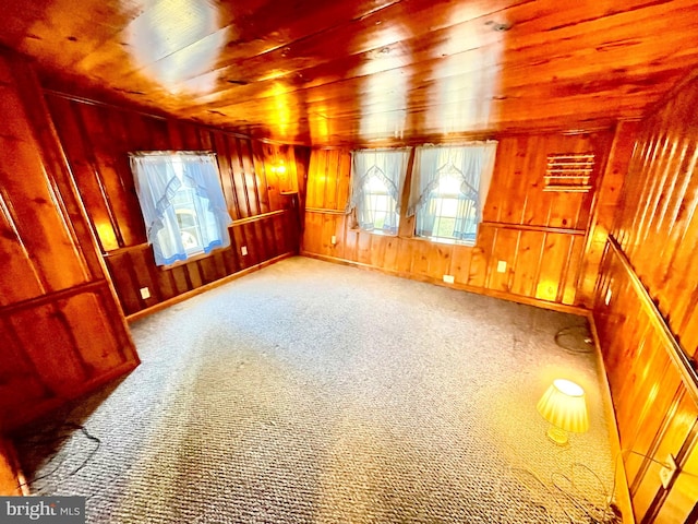 spare room with wood walls, carpet flooring, and wooden ceiling