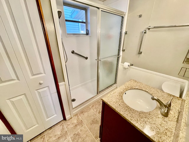 bathroom featuring a shower with door and vanity