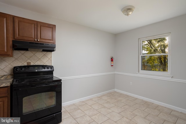 kitchen with dark stone countertops, backsplash, and black electric range