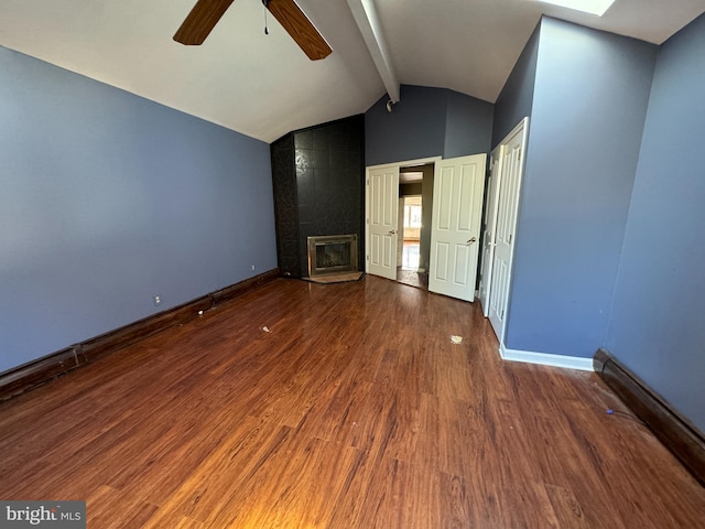 unfurnished living room featuring a baseboard heating unit, a tile fireplace, ceiling fan, lofted ceiling with skylight, and hardwood / wood-style flooring