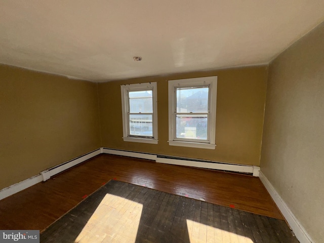 unfurnished room with hardwood / wood-style flooring and baseboard heating