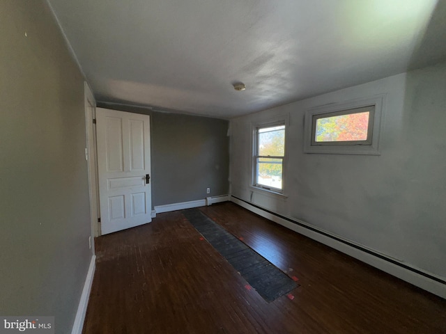 spare room with baseboard heating and dark wood-type flooring