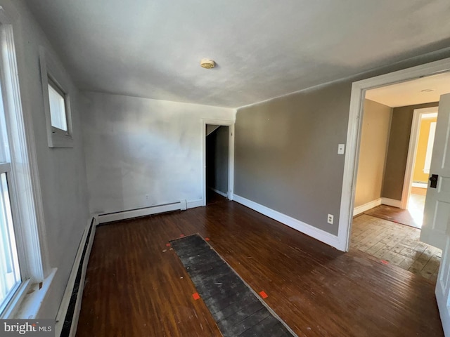 empty room with a baseboard radiator and dark wood-type flooring