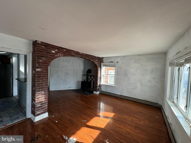 unfurnished living room featuring a baseboard radiator and dark hardwood / wood-style flooring