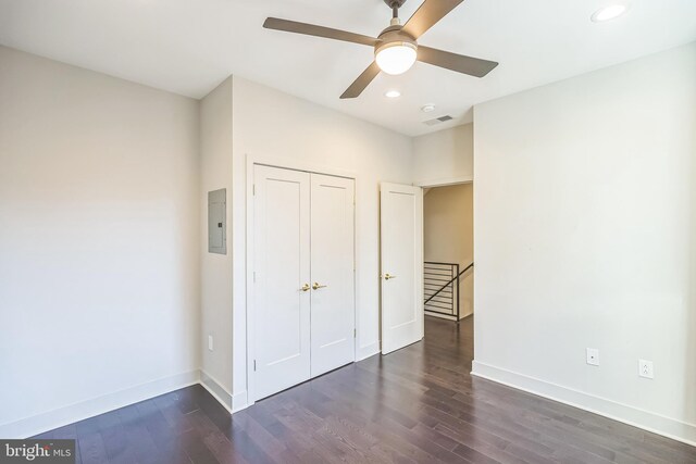 unfurnished bedroom with dark hardwood / wood-style flooring, a closet, electric panel, and ceiling fan