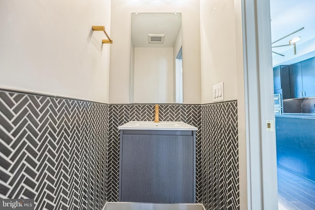 bathroom with vanity and tile walls