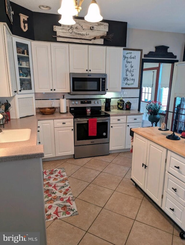 kitchen with appliances with stainless steel finishes, decorative backsplash, white cabinetry, and pendant lighting