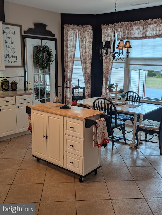 kitchen with a kitchen island, white cabinetry, pendant lighting, and light tile patterned flooring