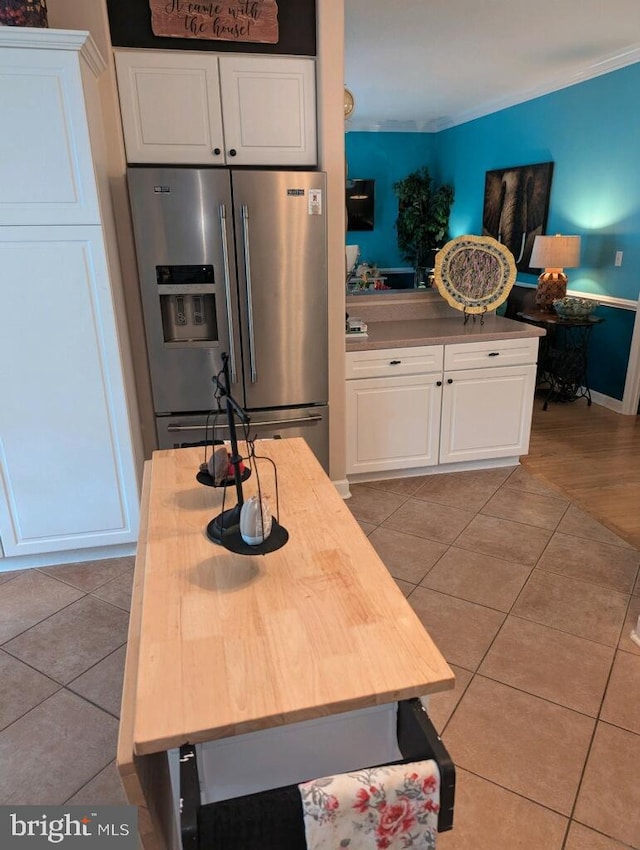 kitchen featuring high end refrigerator, light tile patterned floors, and white cabinets