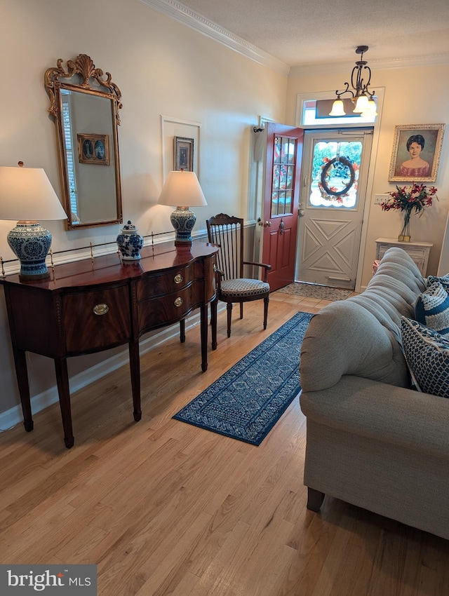 foyer with an inviting chandelier, ornamental molding, and light wood-type flooring