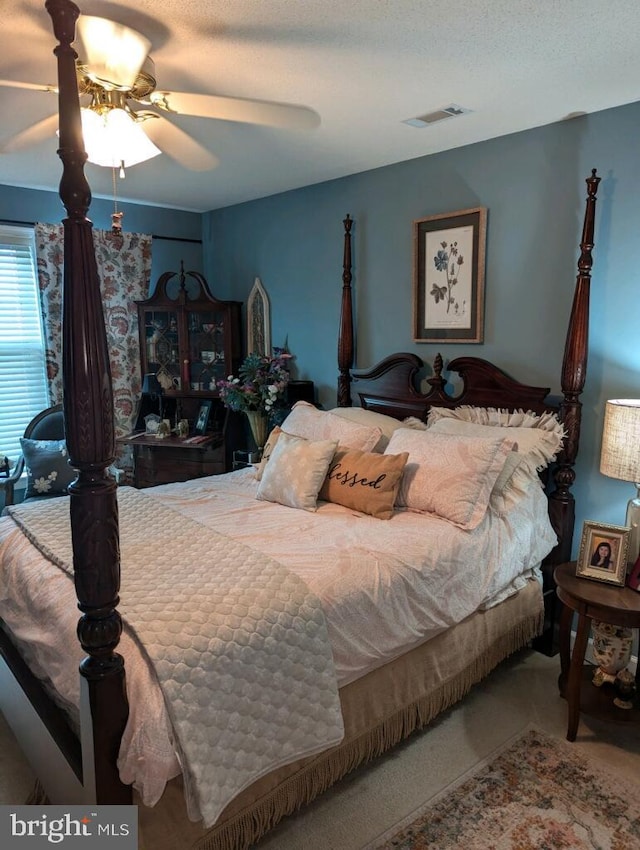 bedroom with a textured ceiling, carpet flooring, and ceiling fan