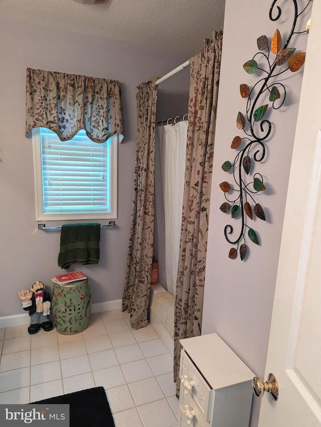 bathroom with tile patterned floors, a textured ceiling, baseboards, and shower / bathtub combination with curtain