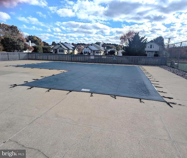 pool with a patio area, fence, and a residential view