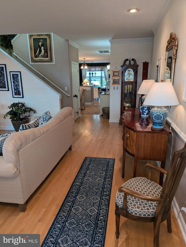 living room featuring hardwood / wood-style flooring, ornamental molding, and an inviting chandelier