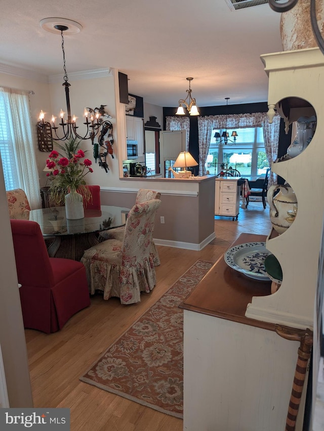 dining area featuring an inviting chandelier, crown molding, and light wood-type flooring