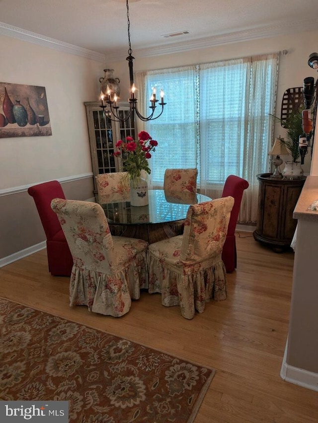 dining area featuring an inviting chandelier, ornamental molding, and hardwood / wood-style floors