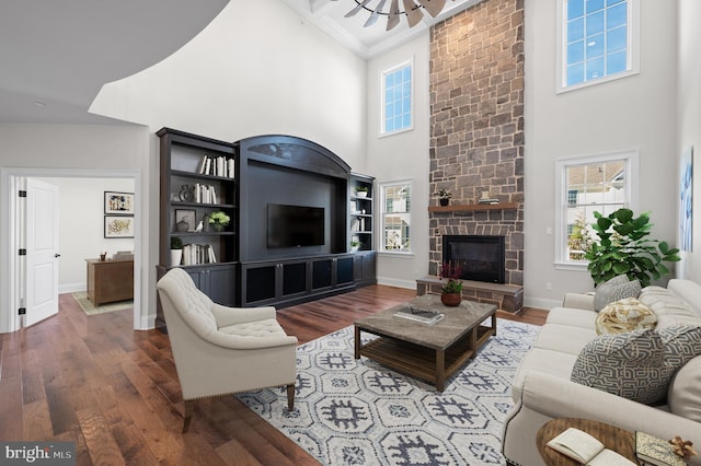 living room featuring a fireplace, hardwood / wood-style flooring, ornamental molding, and a towering ceiling