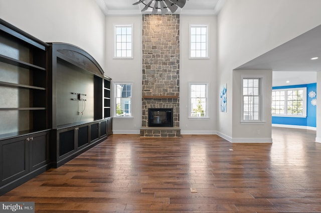 unfurnished living room with a stone fireplace, a wealth of natural light, dark hardwood / wood-style floors, and crown molding