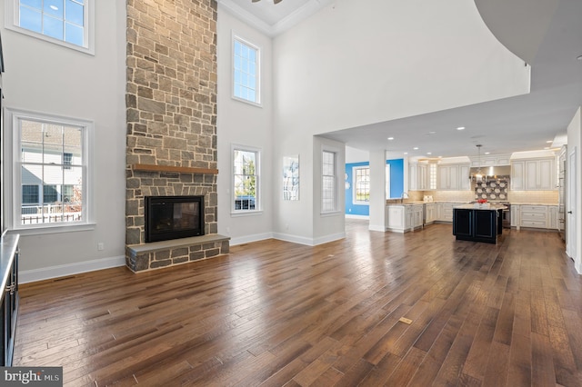 unfurnished living room featuring a towering ceiling, a fireplace, and dark hardwood / wood-style floors