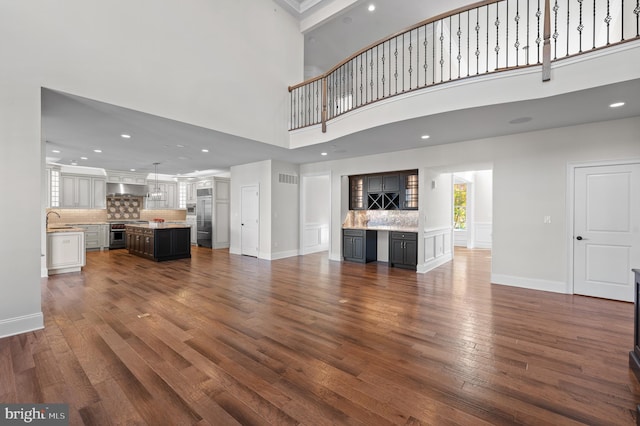 unfurnished living room featuring dark hardwood / wood-style flooring, sink, and a towering ceiling