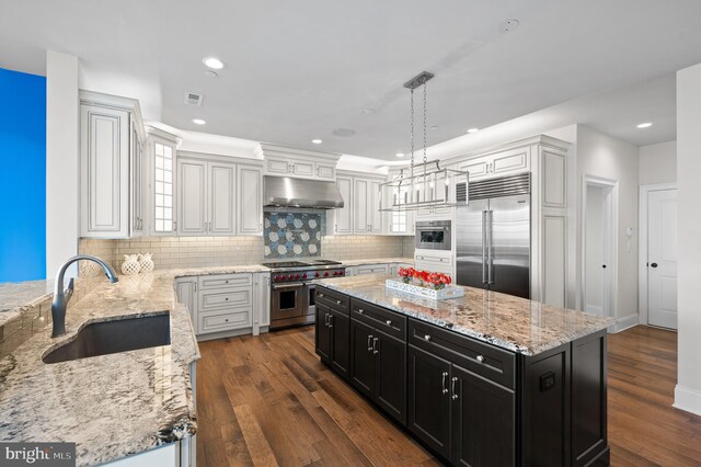 kitchen with decorative light fixtures, dark hardwood / wood-style floors, sink, high end appliances, and a center island