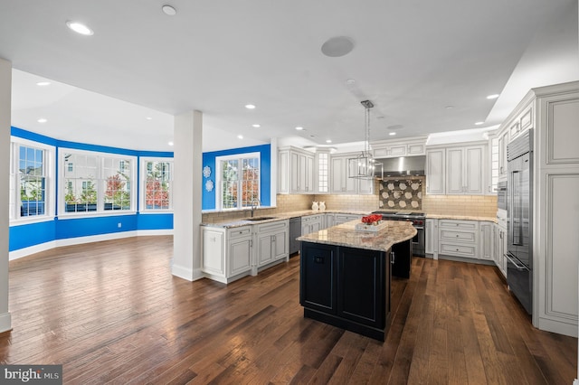 kitchen with light stone counters, a kitchen island, dark hardwood / wood-style flooring, pendant lighting, and high quality appliances