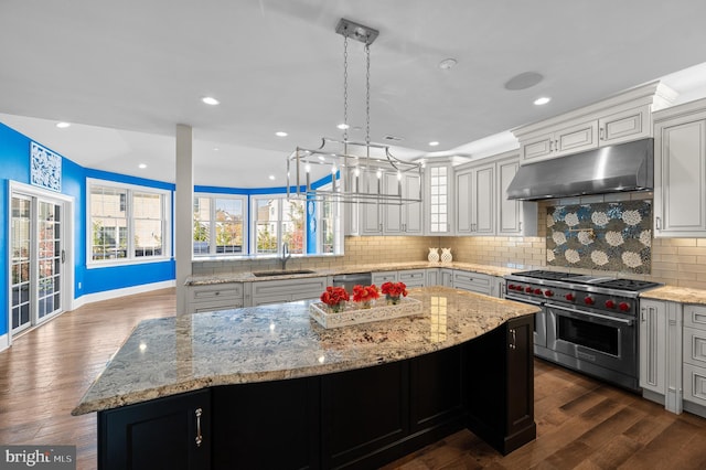 kitchen with dark wood-type flooring, decorative backsplash, a kitchen island, pendant lighting, and appliances with stainless steel finishes